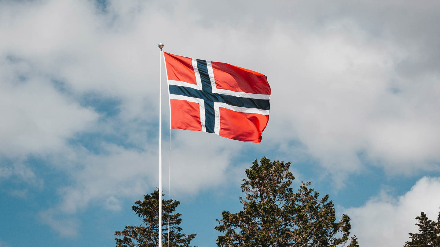 Bildet av norsk flagg som vaier i vind fra flaggstang