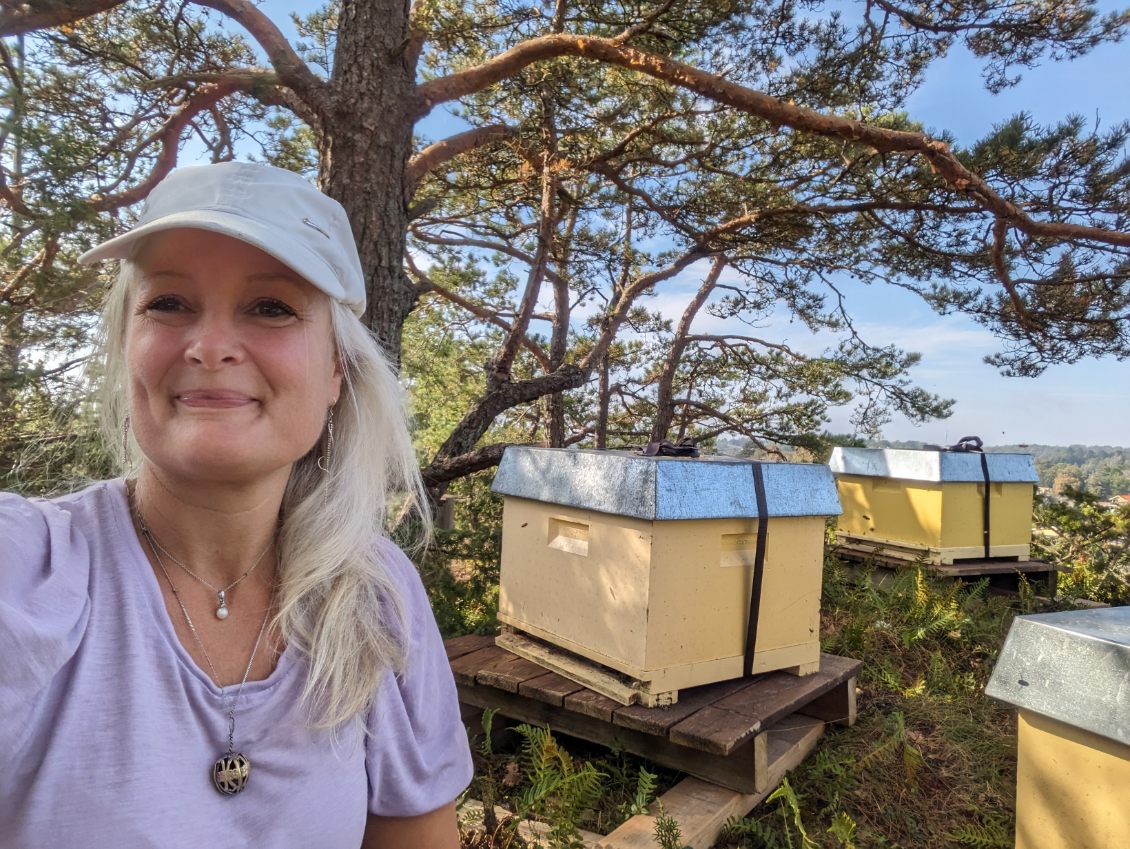 Selfie av kvinnen i artikkelen, som smiler på utsiden av bikubene.
