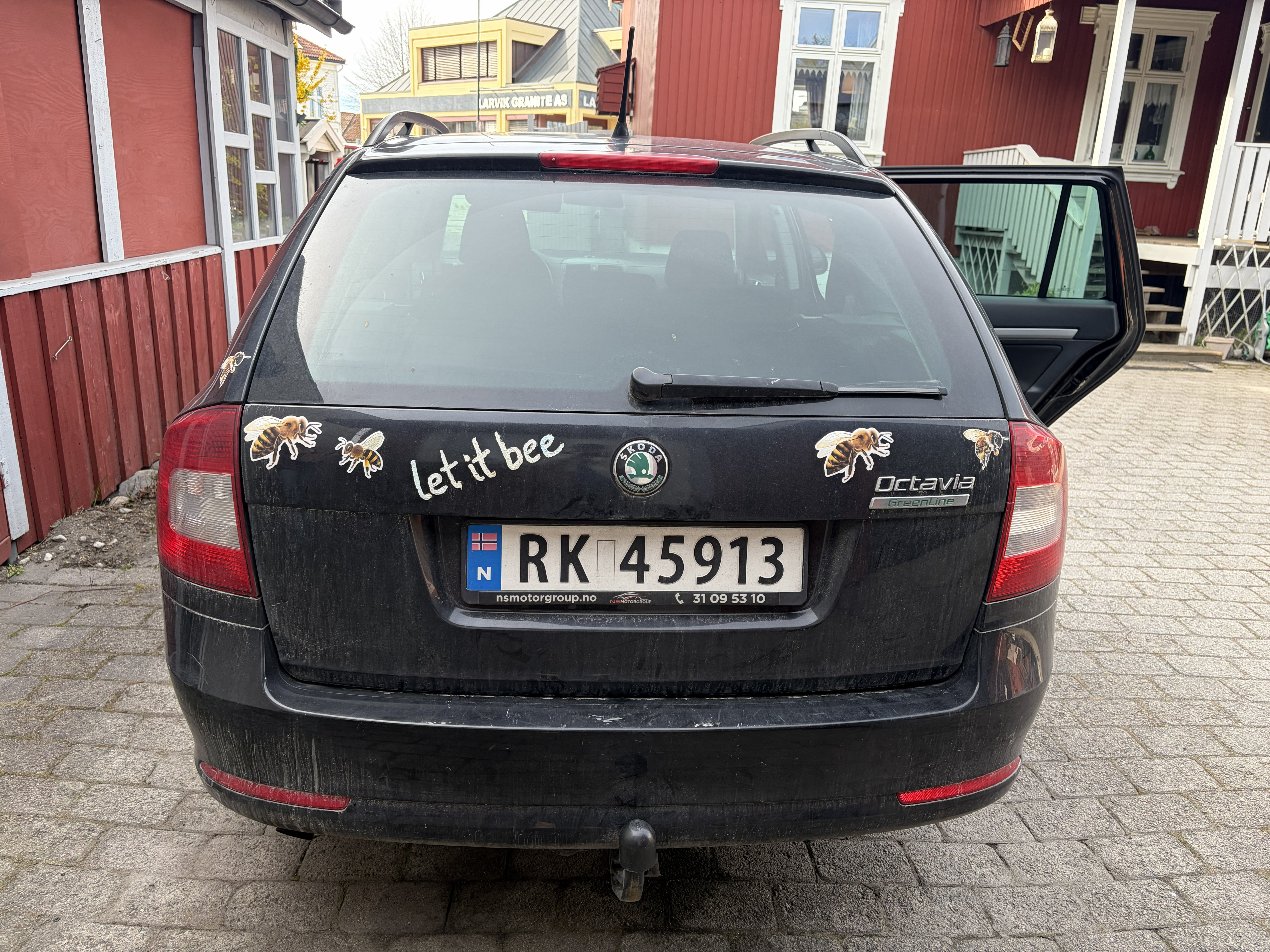 En stasjonsvogn stående i en oppkjørsel, med klistremerket " Let it bee" på.