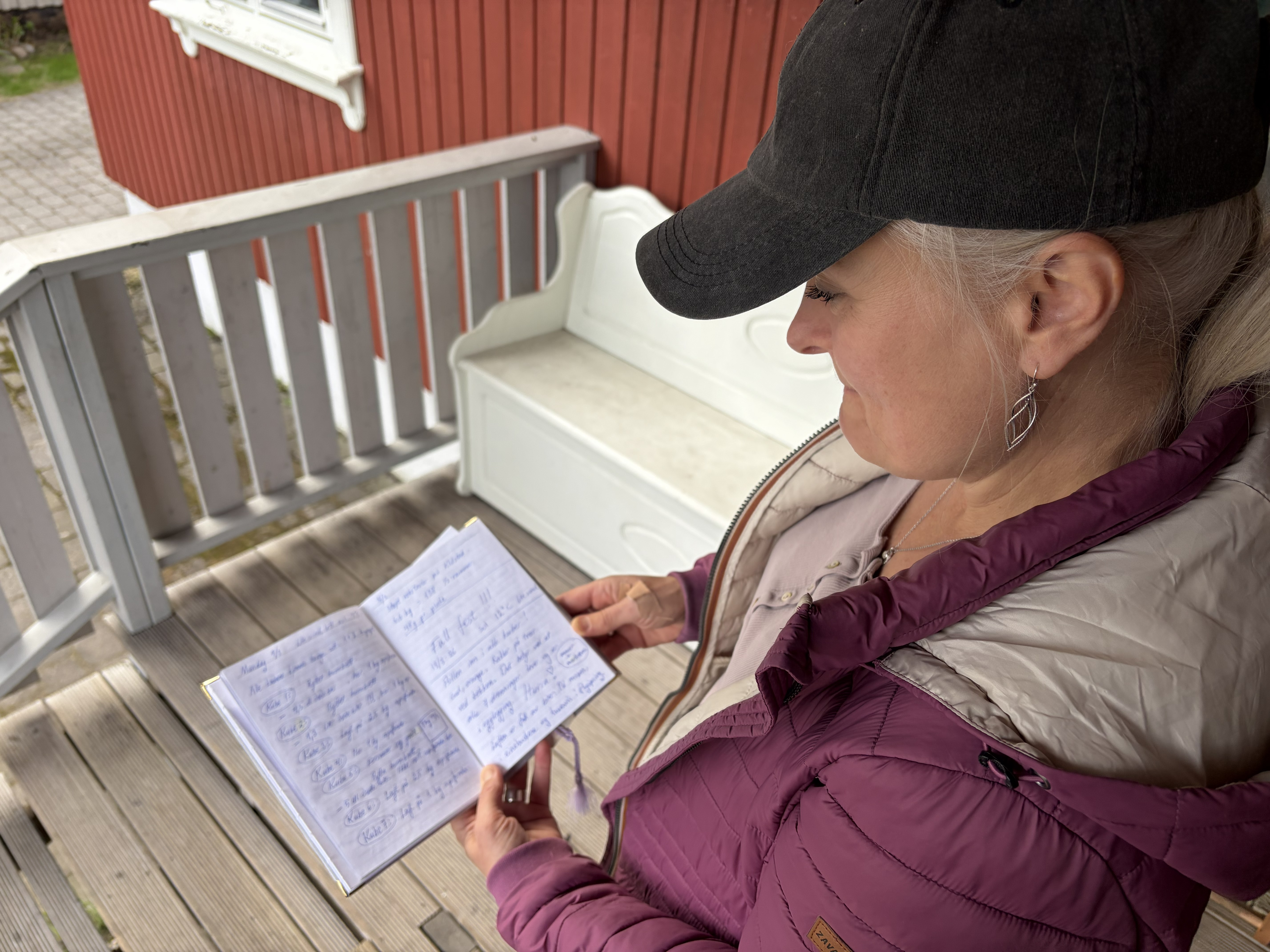 En kvinne med skyggelue leser i en dagbok utendørs.