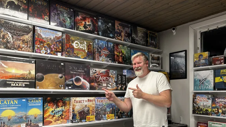 En mann peker på utvalget av brettspill i butikken.